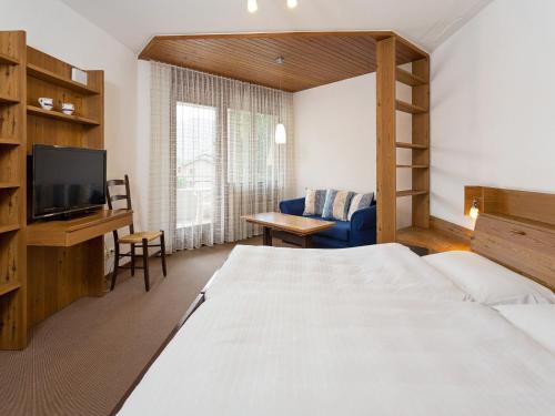 a bedroom with a bed and a tv and a couch at Apartment Resort al Centro-1 by Interhome in Massagno