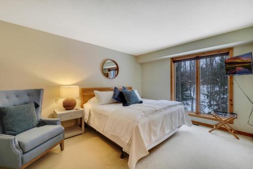 a bedroom with a bed and a chair and a window at The Hidden Chalet in Harbor Springs