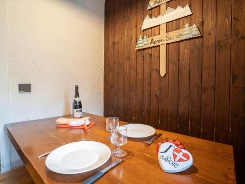 un tavolo in legno con due piatti e una bottiglia di vino di Apartment Armoise 73 by Interhome a Les Menuires