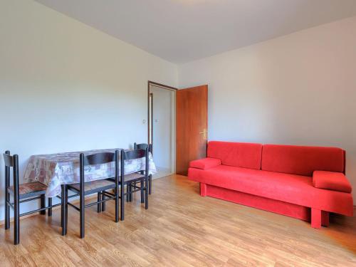 a living room with a red couch and a table at Apartment Vesela-3 by Interhome in Savudrija