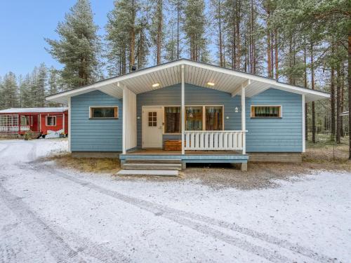 a blue house with a porch in the woods at Holiday Home Villa kuusanka by Interhome in Kuusamo