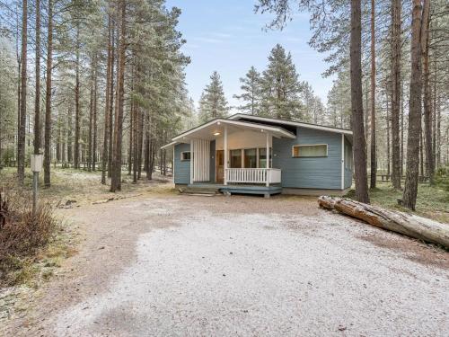 a small blue house in the middle of a forest at Holiday Home Villa hilla by Interhome in Kuusamo