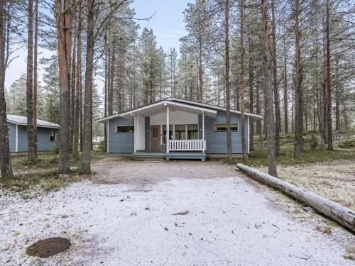 ein blaues Haus mit einer Veranda im Wald in der Unterkunft Holiday Home Villa lakka by Interhome in Kuusamo