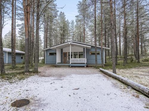 a blue house with a porch in the woods at Holiday Home Villa lakka by Interhome in Kuusamo