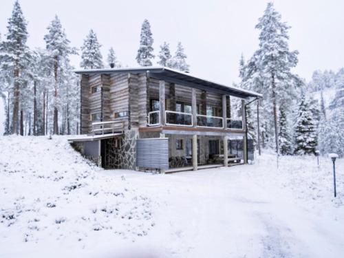 a log cabin in the snow with trees at Holiday Home Leija by Interhome in Ruka