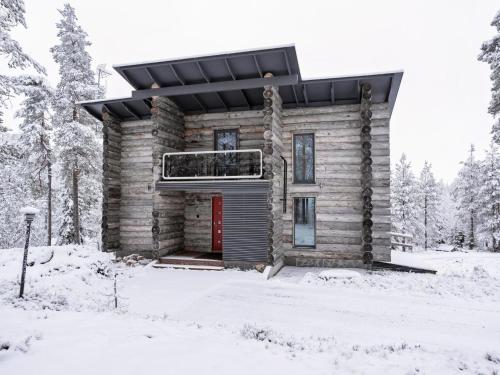 a log cabin in the snow with a red door at Holiday Home Leija by Interhome in Ruka
