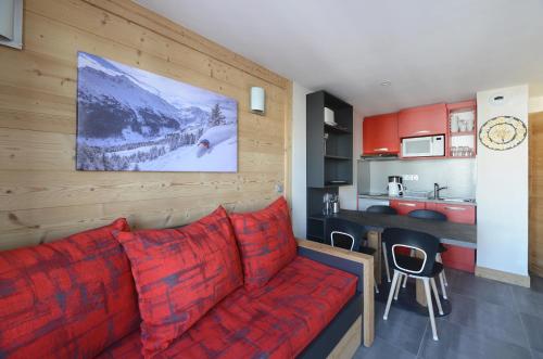 a living room with a red couch and a kitchen at Noemys Backgammon in La Plagne