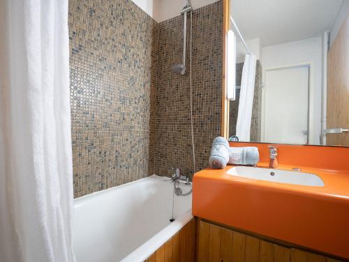 La salle de bains orange est pourvue d'une baignoire et d'un lavabo. dans l'établissement Studio Chavière 617 by Interhome, aux Menuires