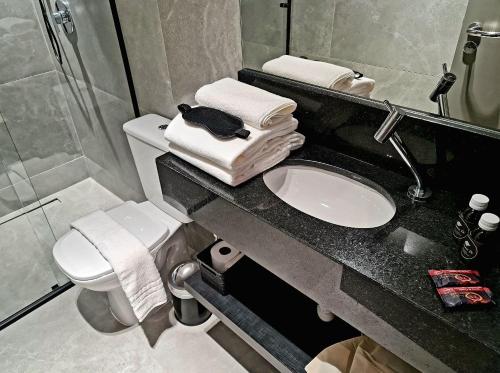 a bathroom with a sink and a toilet and towels at Seasons BC in Cabeçudas