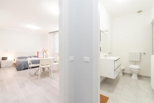 a white bedroom with a bed and a bathroom at Palazzetto Vittoria - F&L Apartment in Brescia