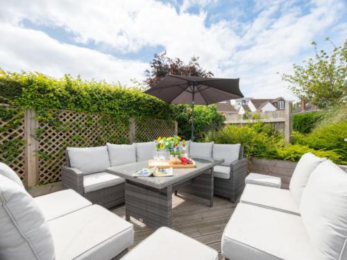 a patio with white furniture and an umbrella at Holiday Home Driftwood by Interhome in Shaldon