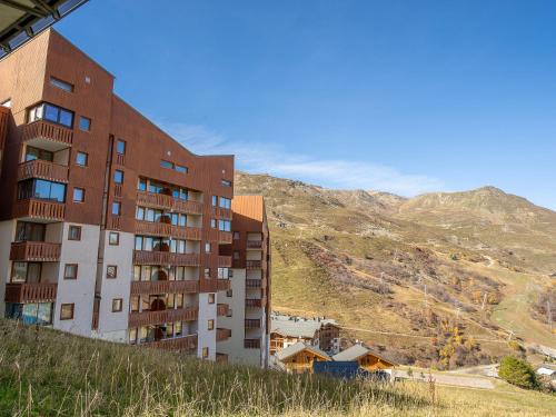 un bâtiment sur une colline avec une montagne en arrière-plan dans l'établissement Apartment Ski Soleil 1 - 1511 by Interhome, aux Menuires