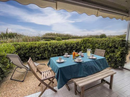 - une table avec un chiffon bleu et des chaises sur la terrasse dans l'établissement Studio Les Terrasses de la Mer-17 by Interhome, à La Grande Motte