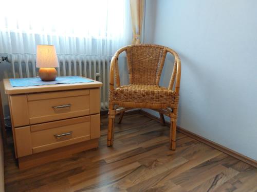 a wicker chair sitting next to a dresser with a lamp at Ferienwohnung Gaul in Riedenburg