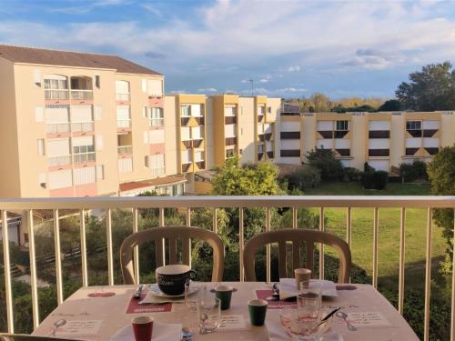 une table sur un balcon avec vue sur les bâtiments dans l'établissement Apartment Terrasses de la Baronnie-5 by Interhome, au Grau-du-Roi