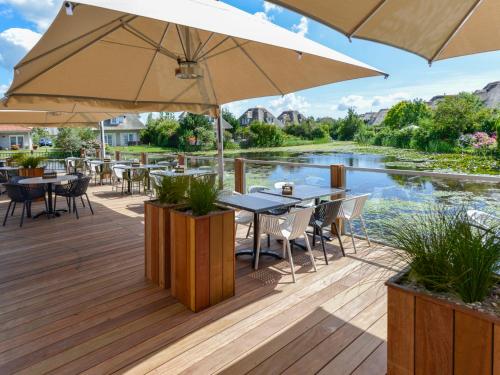 a deck with tables and chairs and an umbrella at Holiday Home Citta Romana-1 by Interhome in Hellevoetsluis