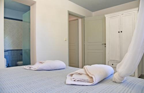 a white bedroom with two towels on a bed at Alexandrea, family home near Vourkari on the island of Kea in Ioulida