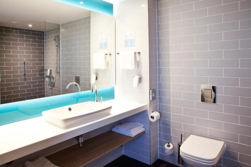 a bathroom with a sink and a toilet and a mirror at Holiday Inn Express & Suites - Basel - Allschwil, an IHG Hotel in Basel