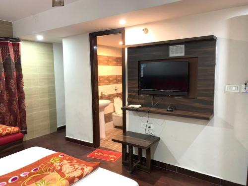 a living room with a tv and a bed and a couch at Hotel Sukhman Residency in Amritsar