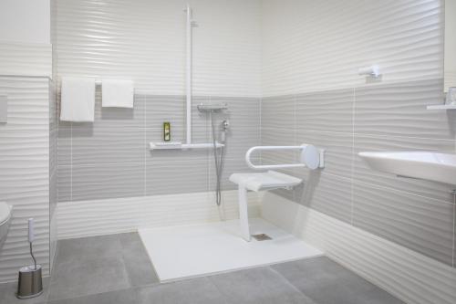 een witte badkamer met een douche en een wastafel bij Logis REX HOTEL Lorient in Lorient