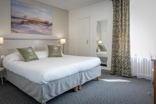 a bedroom with a large white bed with green pillows at Logis REX HOTEL Lorient in Lorient