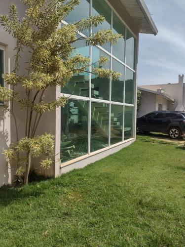 a building with a large glass window next to a tree at Sítio da Vó Lena - Alto Caparaó MG in Alto Caparao