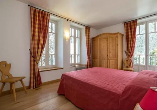 a bedroom with a red bed and windows at La Grande Savoyarde in Chamonix