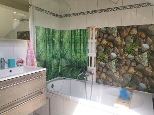 La salle de bains est pourvue d'une douche et d'une baignoire avec une fresque murale. dans l'établissement Mevazara guesthouse, à Malmedy