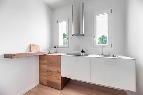 a white kitchen with a sink and two windows at Palazzo '900 Design Flats - Il Poeta in Padova