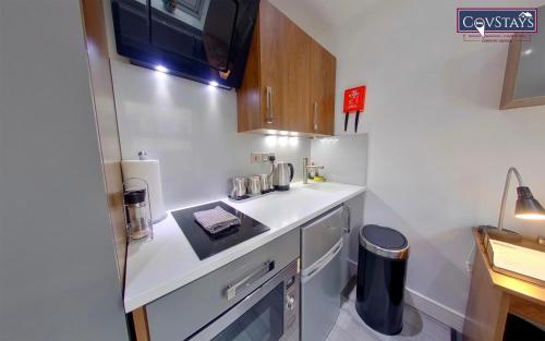 a small kitchen with a counter and a sink at Victoria House - Deluxe Studios in Coventry City Centre, free parking, by COVSTAYS in Coventry