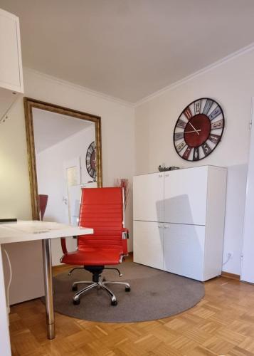 an office with a red chair and a clock on the wall at Haus - Bonsai Bonsai Apartments I in Bad Pyrmont