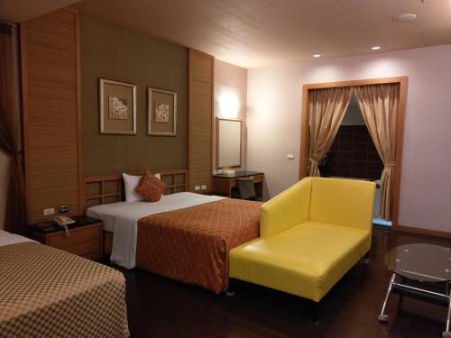a hotel room with two beds and a yellow chair at Lisa Motel in Kaohsiung