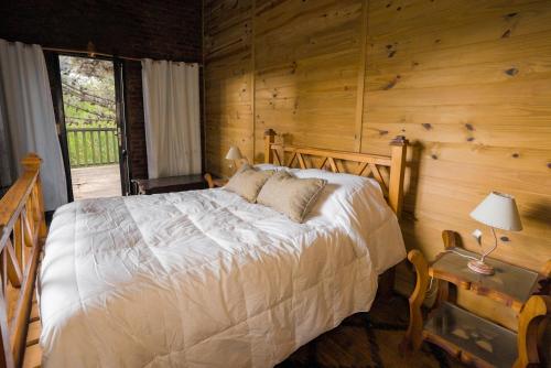 1 dormitorio con 1 cama en una cabaña de madera en Kimba Bosque en Mar de las Pampas