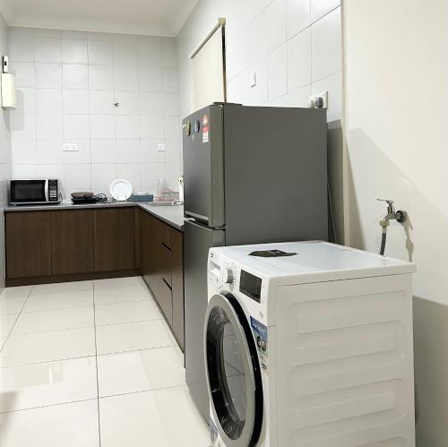 a kitchen with a washing machine and a refrigerator at Damen Suite Sunway Subang by DW in Subang Jaya