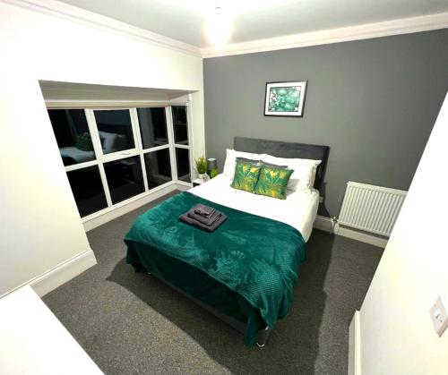 a bedroom with a bed with a green blanket at Chantry Suites in Grimsby