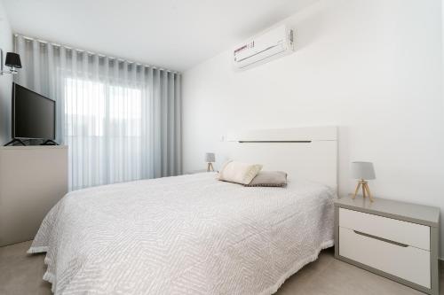 ラゴアにあるNuno & Daisy Apartamento Lagoaのベッドとテレビのある白い寝室