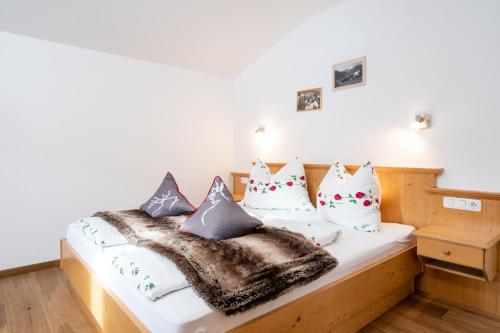 uma cama com um cobertor e almofadas em Ferienwohnung am Waldrand em Mittersill