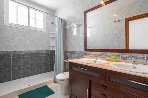 uma casa de banho com 2 lavatórios, um chuveiro e um espelho. em Shangri-La Punta Lara em Nerja
