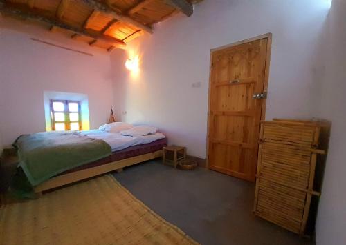 1 dormitorio con 1 cama y puerta de madera en Les Jardins du M'goun, en Kalaat MGouna