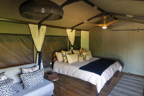 a bedroom with a bed and a couch in a room at TimBila Camp Namibia in Omaruru