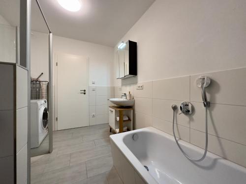 Baño blanco con bañera y lavamanos en Moderne Wohnung mit Küche & Parkplatz Ausblick auf den bayerischen Wald 