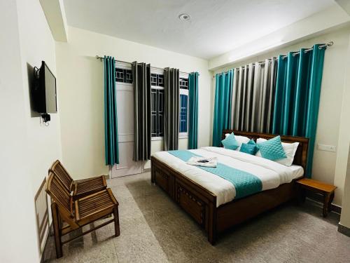a bedroom with a bed with blue curtains and a chair at Radhe Krishna Home Stay Shimla in Shimla