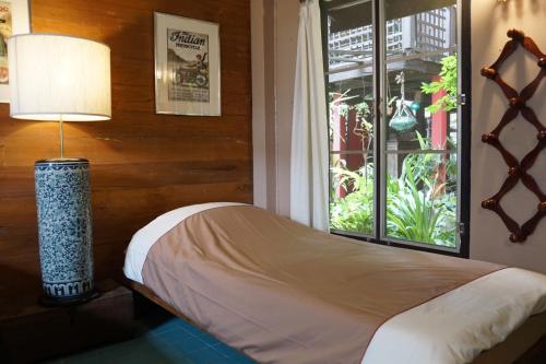 a bedroom with a bed with a lamp and a window at The Riverside Guest House in Lampang