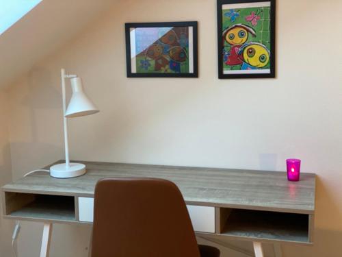 a desk with a lamp and two pictures on the wall at Nyopført luksusværelse i naturskønne og rolige omgivelser in Branderup