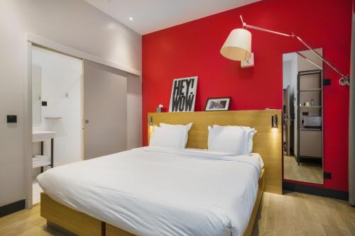 a bedroom with a large bed with a red wall at Maison Nô - Hôtel et Rooftop in Lyon