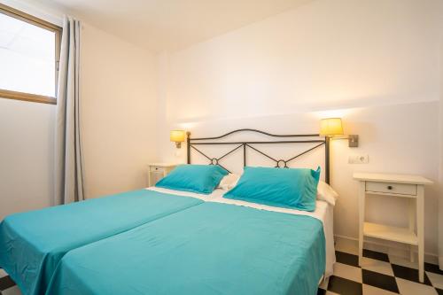 ein Schlafzimmer mit einem Bett mit blauen Kissen und einem Fenster in der Unterkunft Mirada II - Formentera Break in Es Pujols