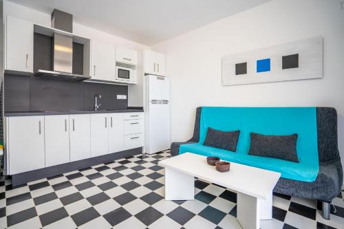 ein Wohnzimmer mit einem blauen Sofa und einem Tisch in der Unterkunft Mirada II - Formentera Break in Es Pujols