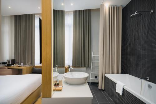 a bathroom with a bed and a tub and a sink at Maison Nô - Hôtel et Rooftop in Lyon