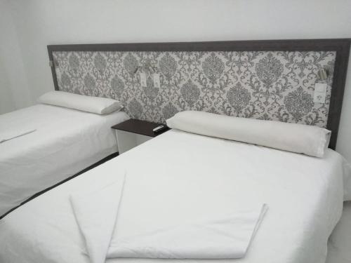 2 camas blancas en una habitación con pared en HELLO HOME FERIA, en Madrid