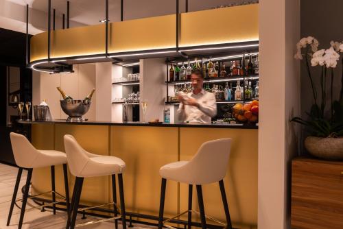 a bar with white stools and a man standing behind it at L'Amirauté Brest in Brest